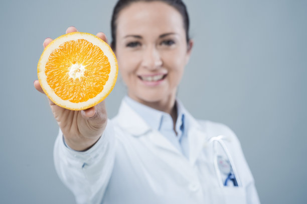 微笑的医生展示一个多汁的橙子图片下载