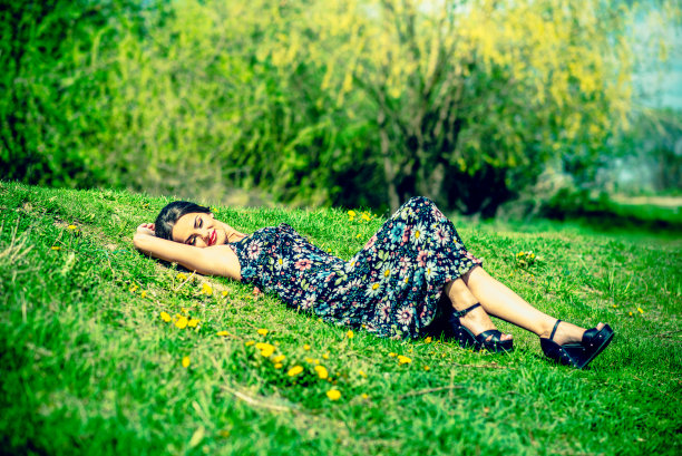 漂亮的黑发女人在公园的草地上休息图片下载
