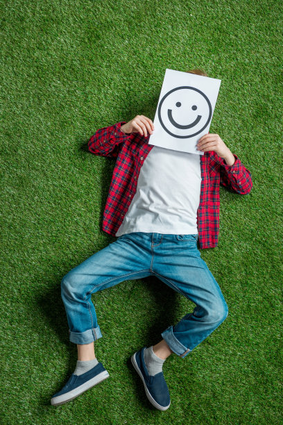 俯视图的孩子躺在草地上，覆盖的脸与图片图片下载