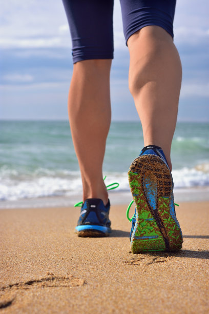 女人的腿，跑步者的腿，海洋的沙滩。图片下载