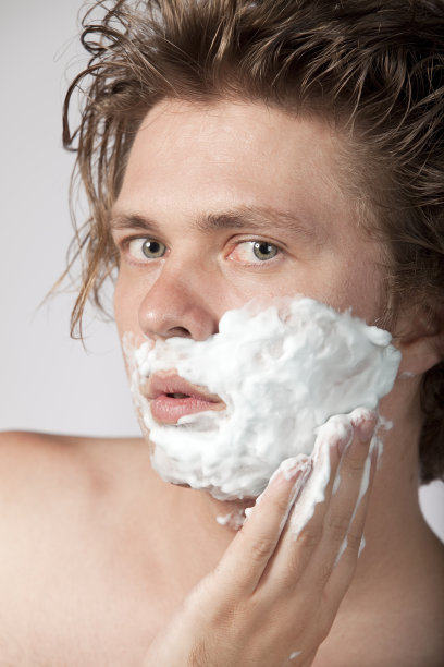 赤裸上身的年轻人在脸上涂抹剃须泡沫图片下载