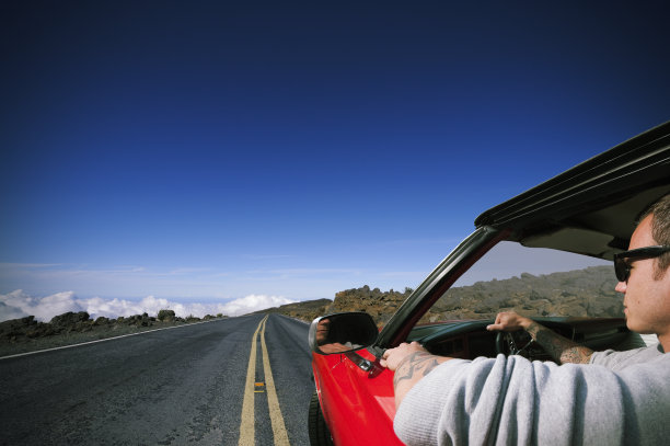 纹身男子驾驶红色肌肉车/毛伊岛-夏威夷图片下载