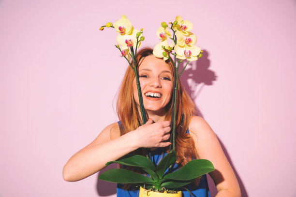 年轻美丽的微笑女孩闻着花香。图片下载