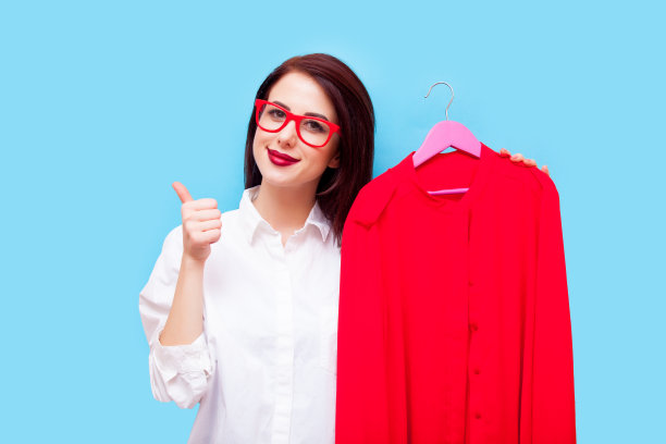 美丽的年轻女子与衬衫衣架站在美妙的蓝色背景图片下载