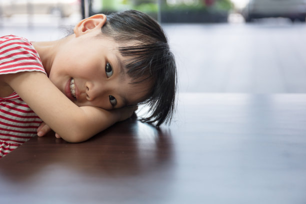 亚洲华人小女孩躺在桌子上图片下载