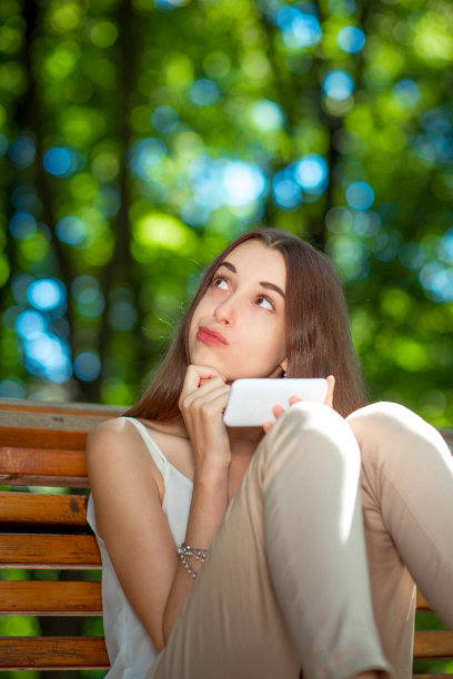 在公园里拿着手机的年轻女子图片下载