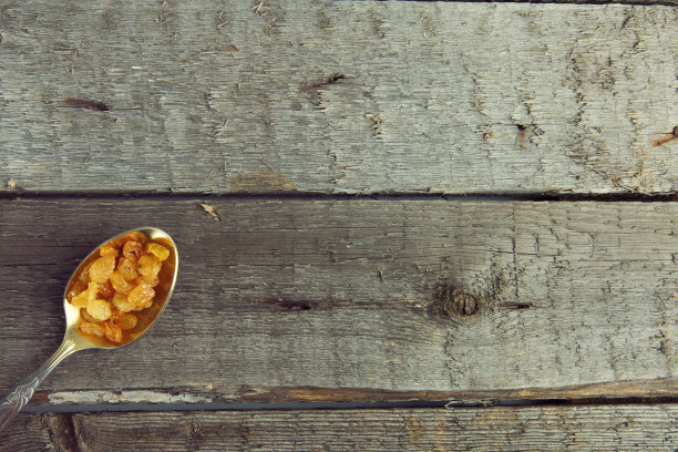 棕色桌子上的金属勺子里的葡萄干照片图片下载