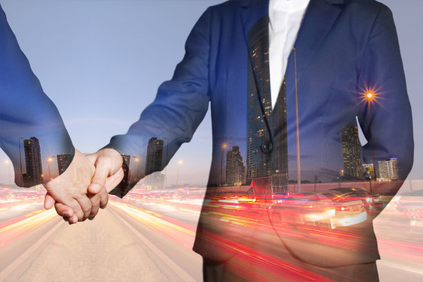 女商人握手的双重曝光，夜晚街道上的灯光痕迹图片下载