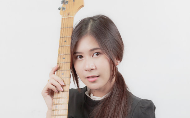 年轻的亚洲女人喜欢弹吉他的肖像，孤立在白色的背景。图片下载