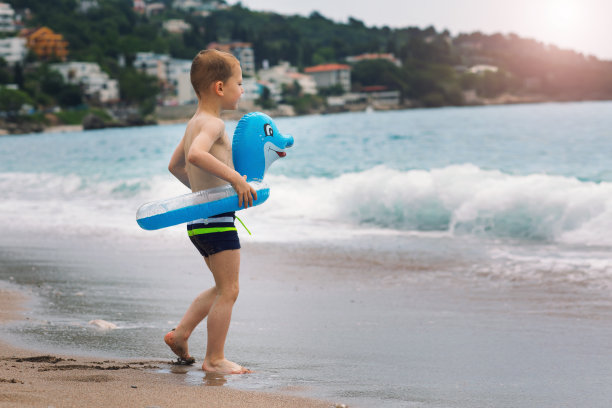 可爱的小男孩戴着五颜六色的橡皮环在夏天的海滩上图片下载
