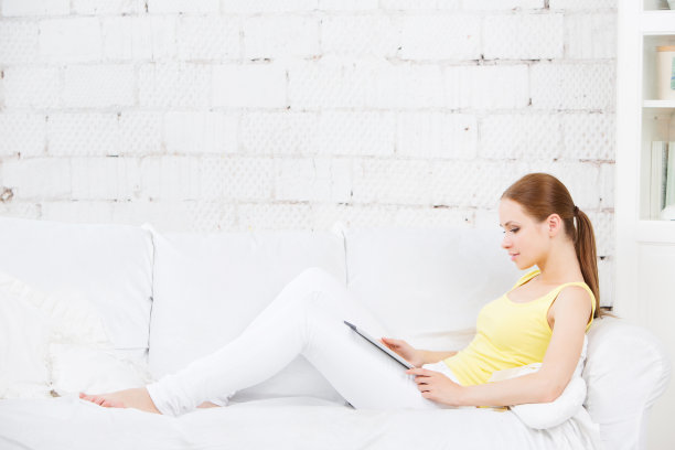 坐在沙发上拿着平板电脑的女孩。乔迁庆宴。图片下载