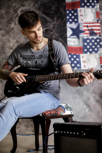 年轻英俊的音乐家弹奏电吉他在黑暗的背景图片下载
