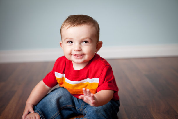 可爱的小男孩坐在硬木地板上的彩色照片图片下载