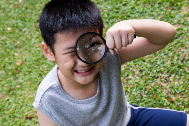 快乐的亚洲华人小男孩透过放大镜看图片下载