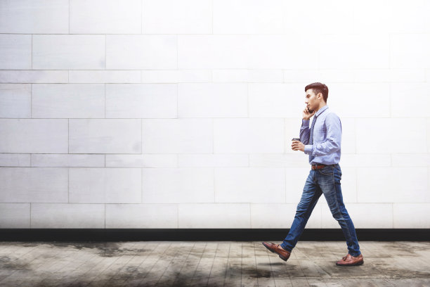年轻的动机商人在户外行走时通过智能手机交谈，现代男性的生活方式在商业理念上使用科技进行沟通图片下载
