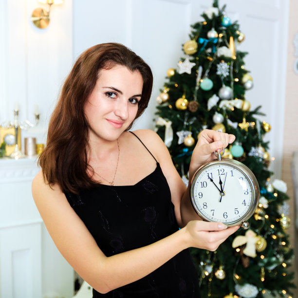 有魅力的年轻女人拿着手表在圣诞室内图片下载