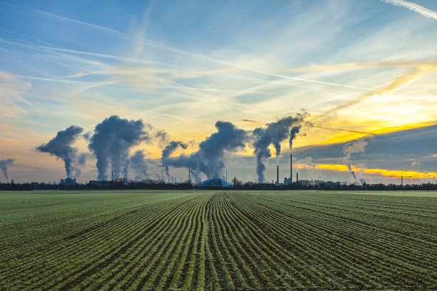 工业工厂的烟囱和烟与田地素材图片