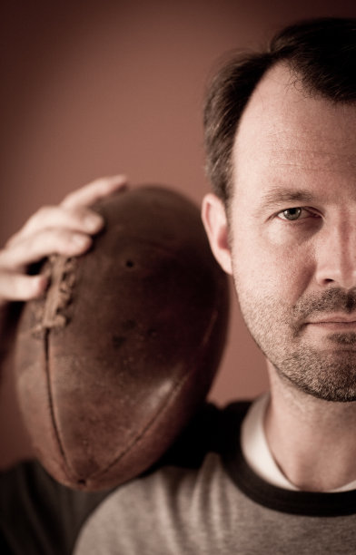 复古足球运动员在肩膀上拿着球的彩色照片图片下载