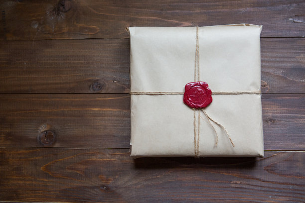 礼品用牛皮纸包好，用细绳系好，用胶粘蜡封好。躺在桌子上放文字的地方图片下载