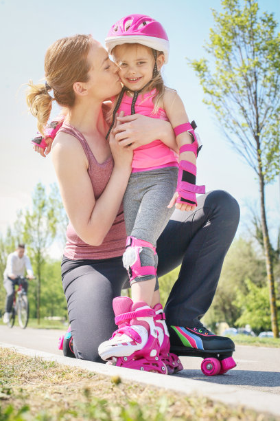 妈妈和她的小女儿在人行道上滑直排轮。母亲和女儿在享受春天的一天。图片下载