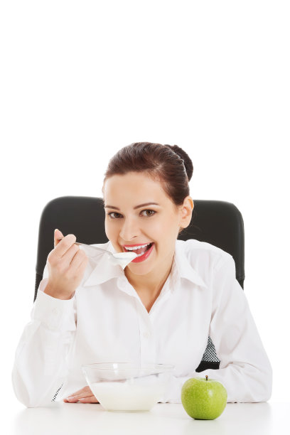 年轻漂亮的女商人坐着吃苹果。图片下载