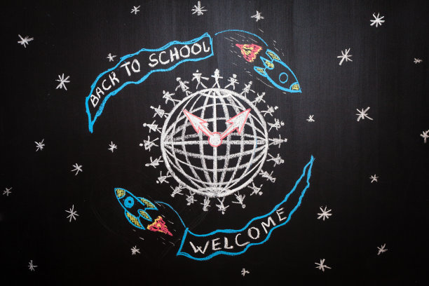 回到学校背景与宇宙飞船与标题为“回到学校”和“欢迎”是围绕地球飞行由白色粉笔写在黑色学校黑板上图片下载