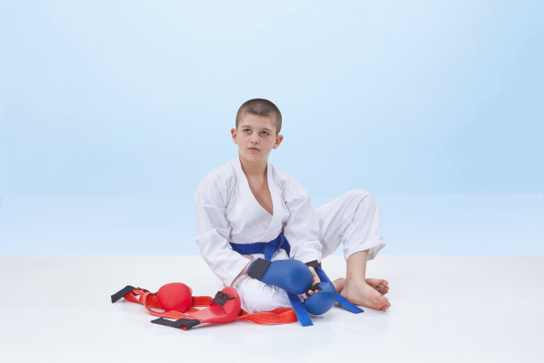 一名身穿空手道的运动员坐在一套空手道装备旁边图片下载