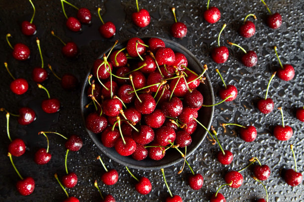 黑盘黑桌上的甜樱桃，表面有水滴图片下载