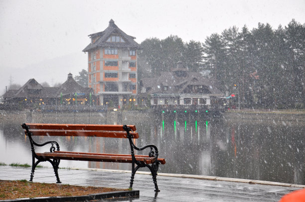 冬天，当雪开始落下的时候，湖边的一个晚上的单张长椅图片下载