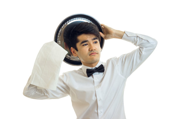 穿着制服打着领结的有趣的年轻侍者看着一边图片下载