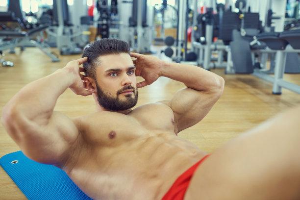 有胡子的健美运动员在地板上做腹肌锻炼图片下载