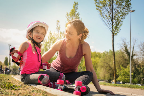 滑冰后，微笑的母亲和她的小女儿坐在路上。图片下载