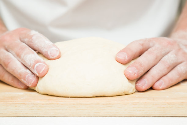 厨师的手在木板上揉面团。准备烘烤。图片下载