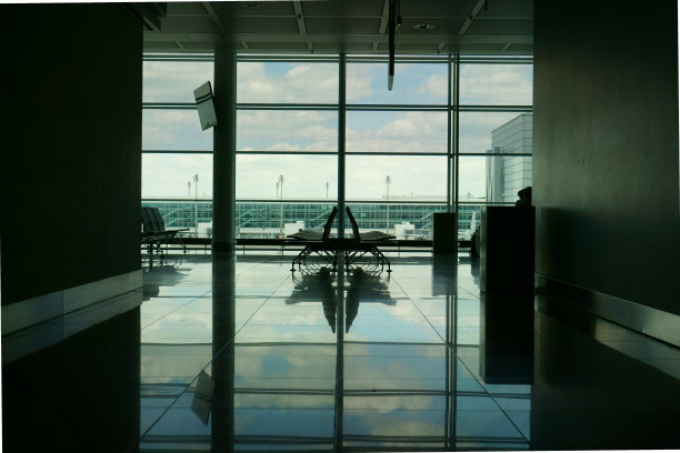 离机场窗口不远的空座位，在候机室里可以看到天空和云朵的倒影图片下载