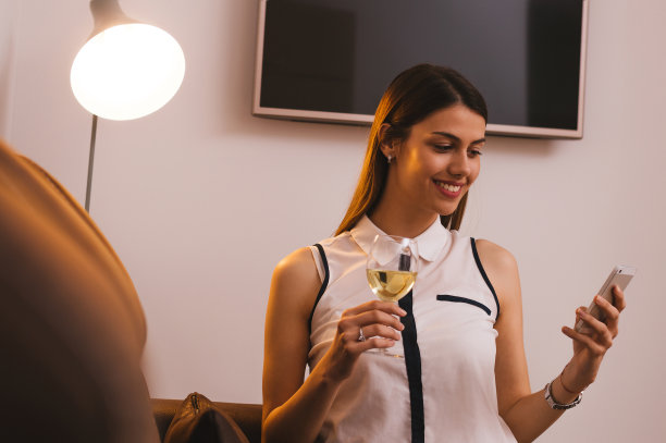 年轻迷人的女孩喝着酒，拿着手机图片下载