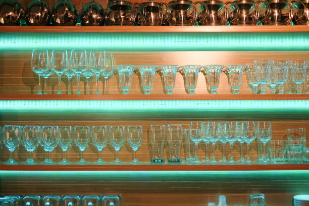 吧台上有各种各样的玻璃，在夜晚的酒吧背景下图片下载