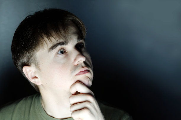 有思想的年轻人肖像在黑暗的背景图片下载