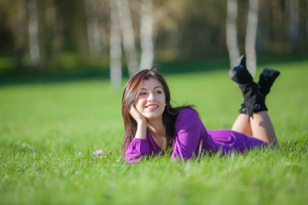 美丽的年轻女子躺在草地上图片下载