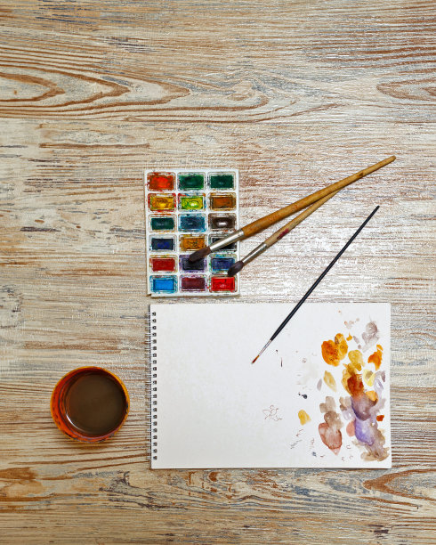桌上放着颜料、画笔和速写本。图片下载