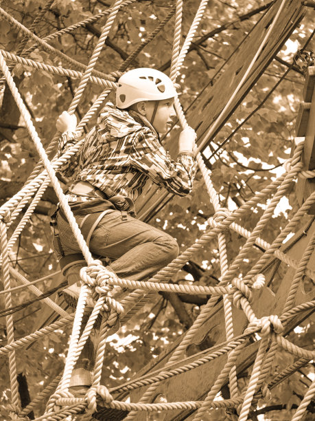 一个戴着头盔的小男孩爬上了钢索图片下载