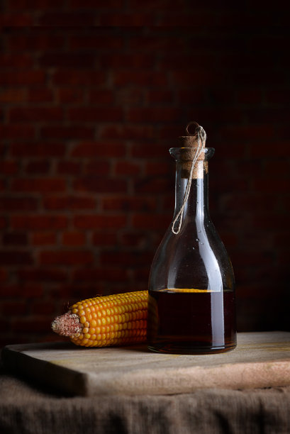 玻璃瓶里的色拉油和红色方块背景上的玉米。图片下载