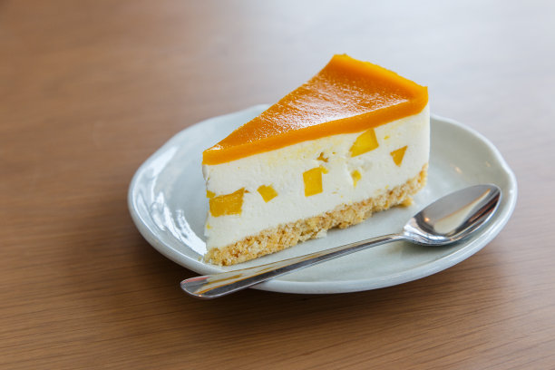 木头背景上的一块芒果奶酪蛋糕图片下载