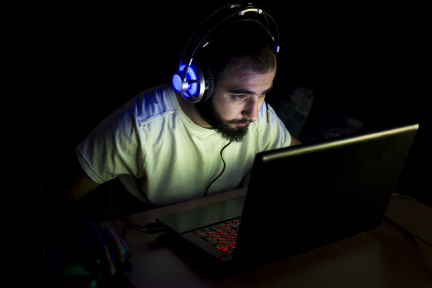 年轻玩家戴着耳机玩电子游戏。素材图片