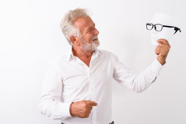 快乐的长胡子的老男人的侧面视图微笑着，看着白色的背景与眼镜的白色面具图片下载