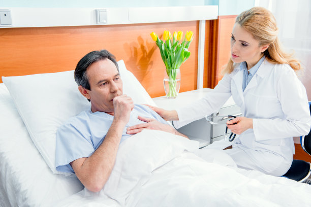中年人胸部疼痛躺在床上，医院里带听诊器的医生坐在他旁边图片下载