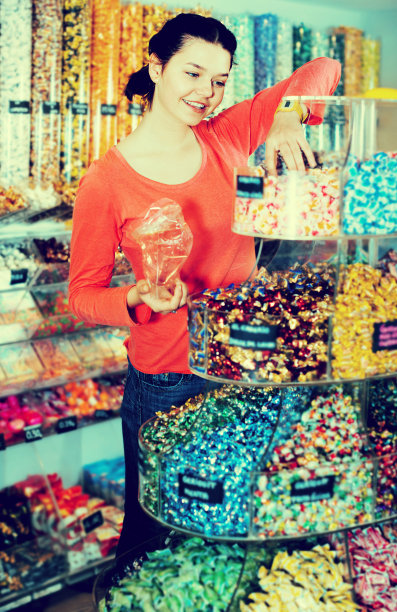 女人对着摄影师摆姿势，挑选不同的糖果图片下载