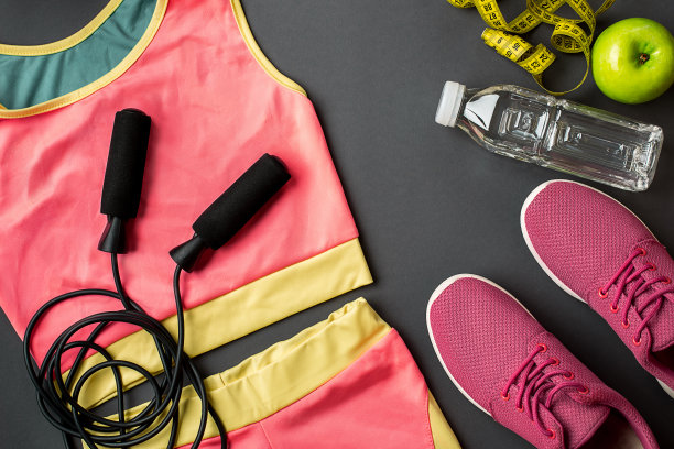 运动员的设置与女性服装，运动鞋和瓶装水在灰色的背景图片下载