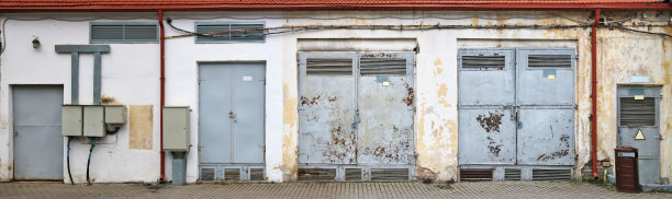 配电大楼的钢锈闸门，金属表面涂有裸露的爆裂灰色油漆。来自几张户外照片的全景拼贴画图片下载