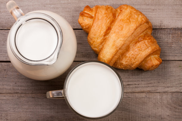 一杯牛奶和羊角面包，背景是古老的木头。俯视图图片下载