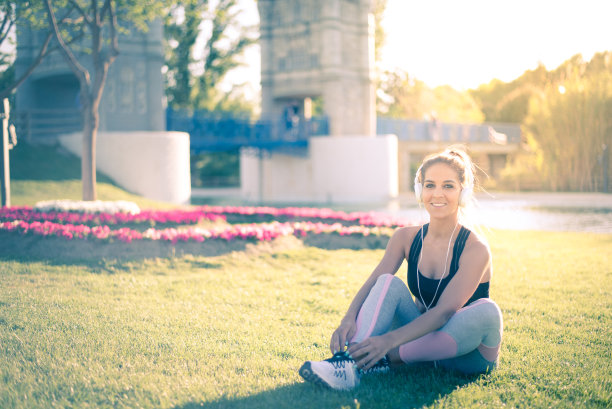 运动妇女做草坪运动和伸展在户外的草地上在公园听音乐图片下载